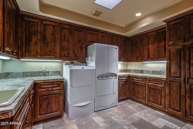 clothes washing area with sink, cabinets, and washing machine and clothes dryer