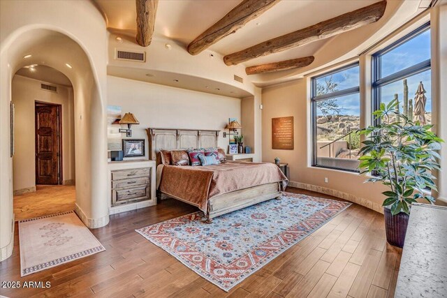 bedroom with hardwood / wood-style floors and beamed ceiling