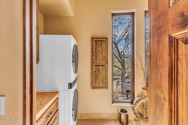 washroom featuring stacked washer and dryer and light tile patterned flooring