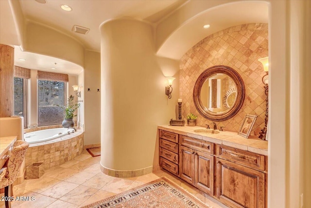 bathroom featuring tasteful backsplash, vanity, and tiled tub