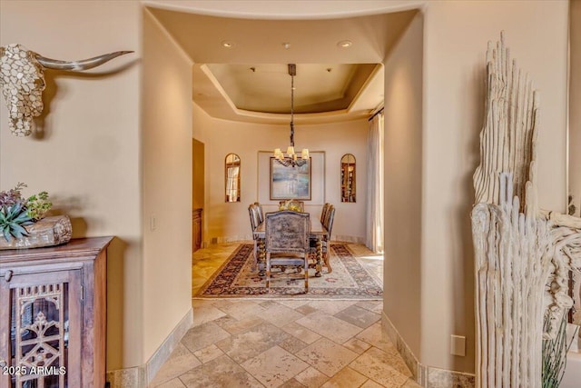 hallway featuring a notable chandelier and a raised ceiling