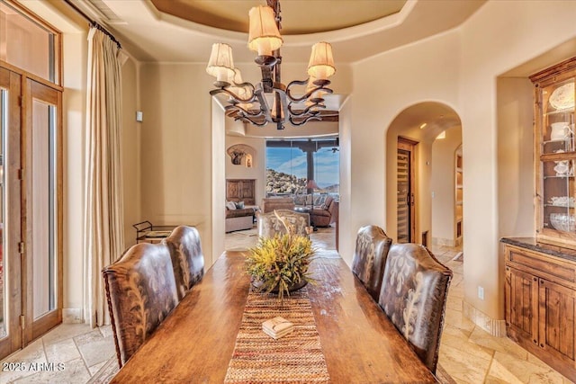 dining space featuring a raised ceiling and a notable chandelier