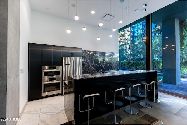 7120 E Kierland Blvd Unit 416, Scottsdale, AZ 85254 - kitchen with stainless steel appliances, dark cabinetry, modern cabinets, a breakfast bar area, and dark stone counters