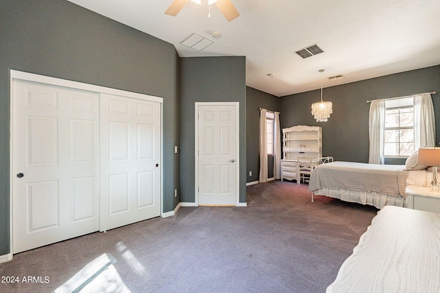 unfurnished bedroom with ceiling fan with notable chandelier, a closet, and dark carpet