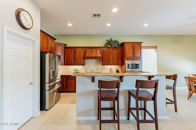 kitchen featuring light stone counters, light tile patterned floors, sink, stainless steel dishwasher, and a kitchen island with sink