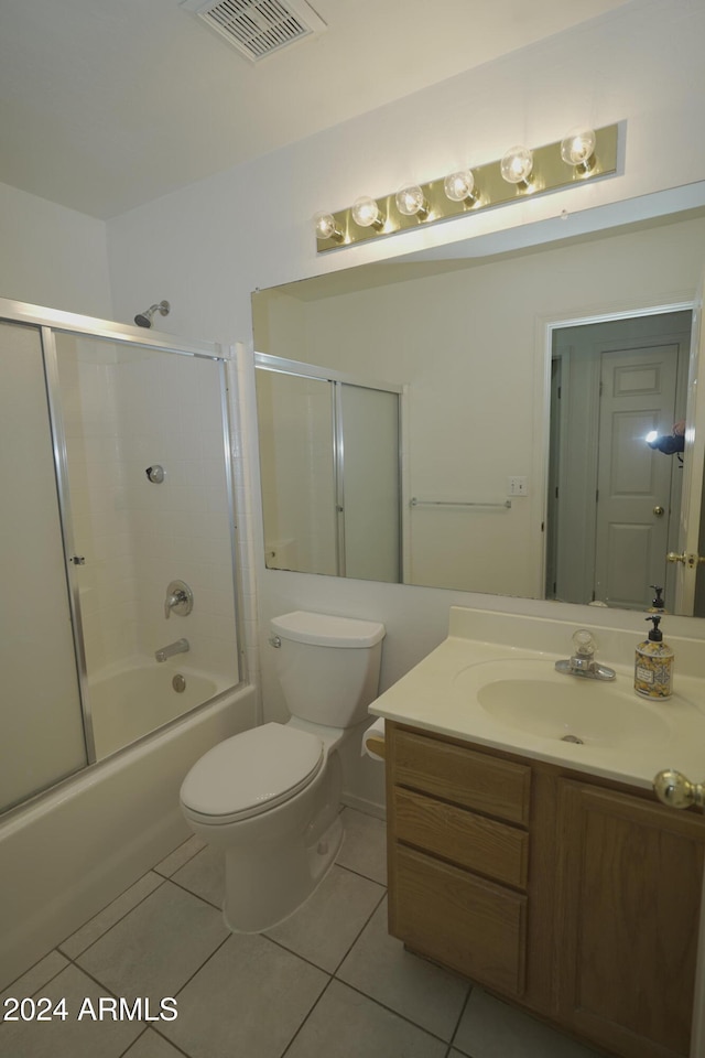 full bathroom with bath / shower combo with glass door, vanity, tile patterned floors, and toilet