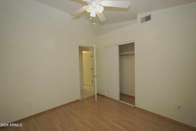 unfurnished bedroom featuring light hardwood / wood-style floors, ceiling fan, a closet, and vaulted ceiling