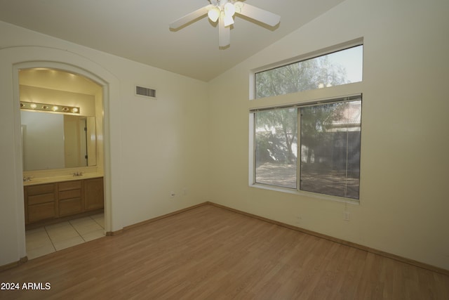 unfurnished bedroom featuring ceiling fan, ensuite bath, light hardwood / wood-style flooring, and lofted ceiling