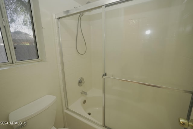 bathroom featuring enclosed tub / shower combo and toilet