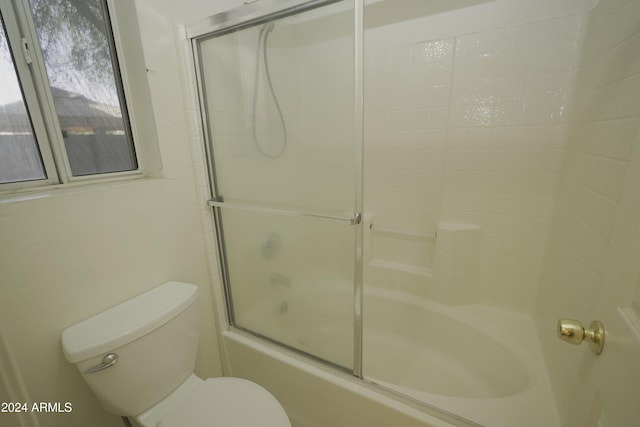 bathroom featuring combined bath / shower with glass door and toilet