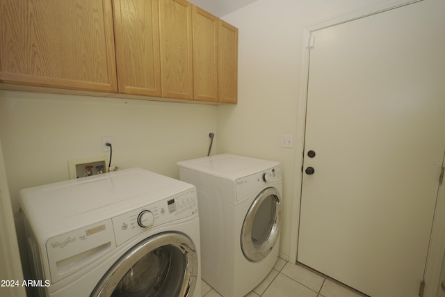 laundry area with washer and clothes dryer, cabinets, and light tile patterned floors