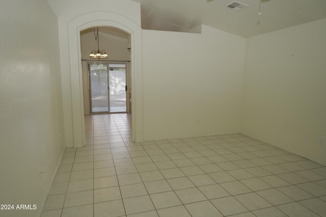 spare room with ceiling fan with notable chandelier, lofted ceiling, and light tile patterned flooring