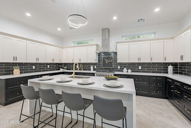 707 E Ocotillo Rd, Phoenix, AZ 85014 - kitchen with island exhaust hood, dark cabinetry, a sink, a kitchen bar, and decorative backsplash