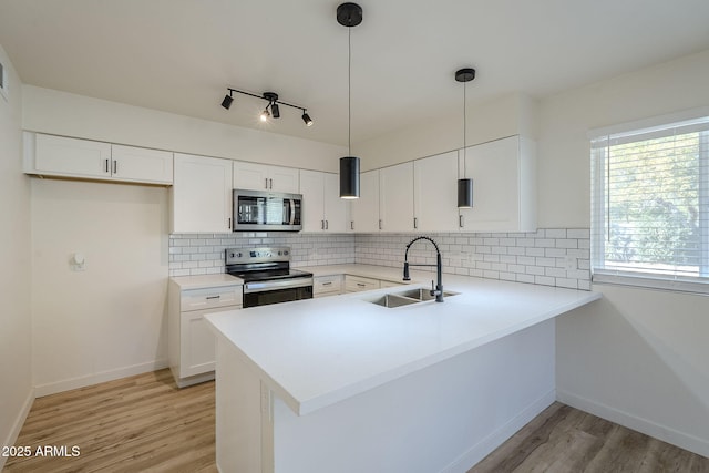 kitchen featuring stainless steel appliances, kitchen peninsula, white cabinets, and decorative light fixtures