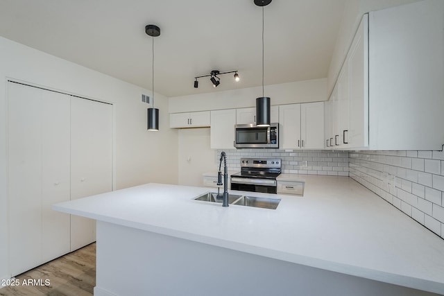 kitchen with hanging light fixtures, white cabinetry, appliances with stainless steel finishes, and kitchen peninsula