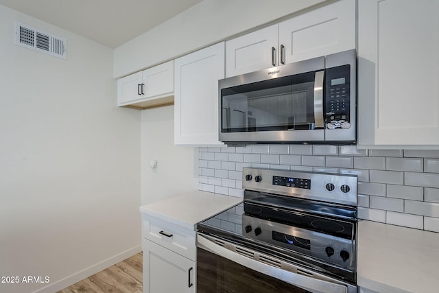 kitchen featuring white cabinetry, stainless steel appliances, light hardwood / wood-style floors, and decorative backsplash