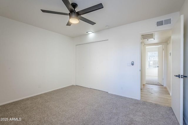 empty room featuring ceiling fan and light colored carpet