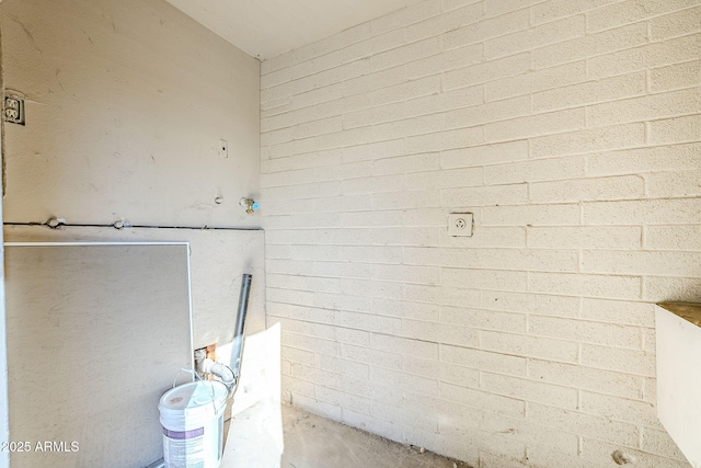 bathroom featuring concrete flooring and brick wall