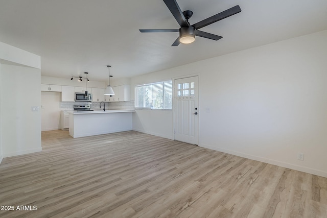 unfurnished living room with ceiling fan, sink, and light hardwood / wood-style flooring