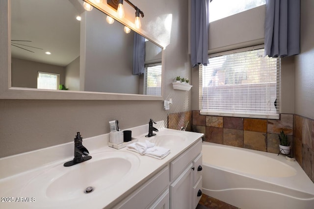 bathroom featuring a healthy amount of sunlight, a bathtub, and vanity