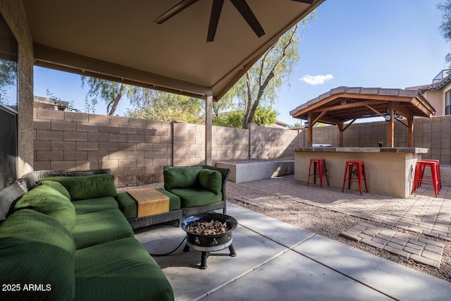 view of patio with an outdoor living space with a fire pit, ceiling fan, and a bar