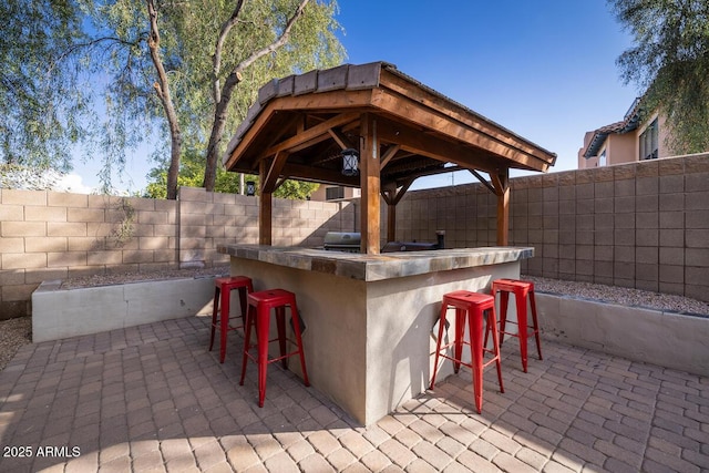 view of patio featuring a bar, a gazebo, and area for grilling