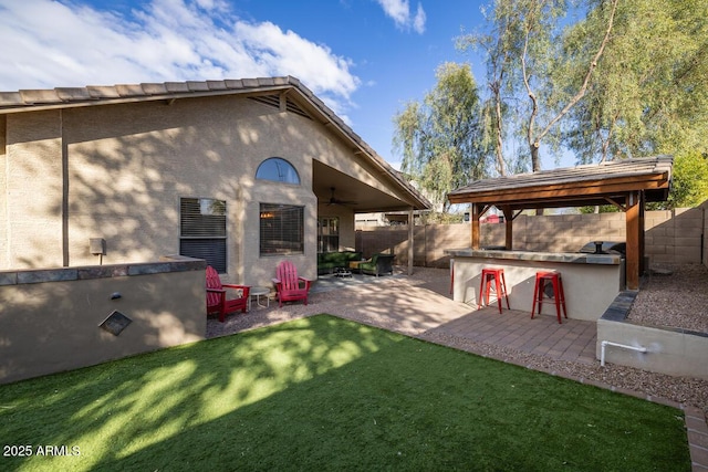 back of property featuring a gazebo, a lawn, ceiling fan, exterior bar, and a patio