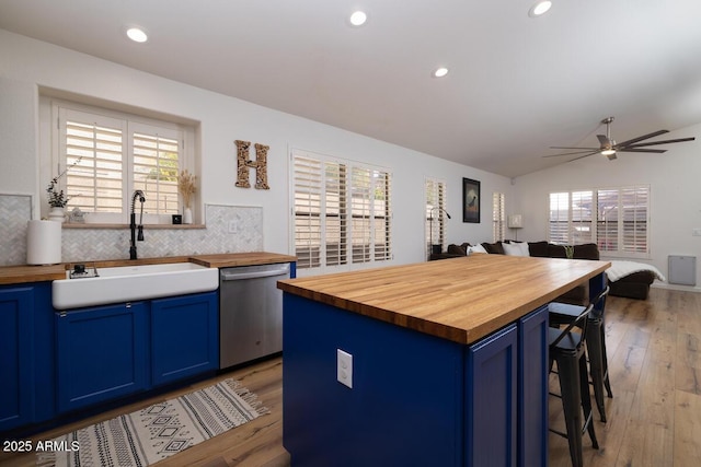 kitchen featuring a kitchen island, dishwasher, butcher block counters, sink, and blue cabinetry