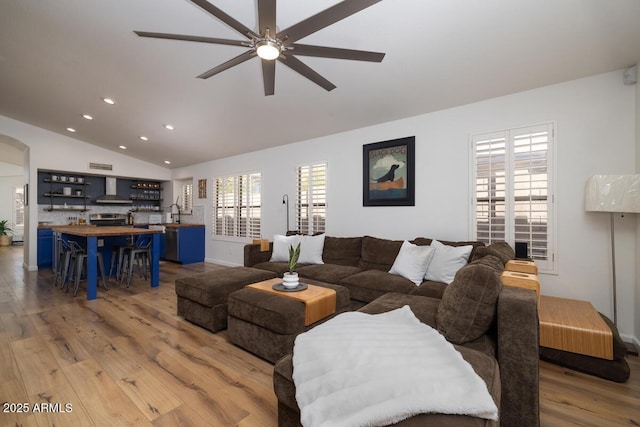 living room featuring ceiling fan, lofted ceiling, sink, and light hardwood / wood-style flooring