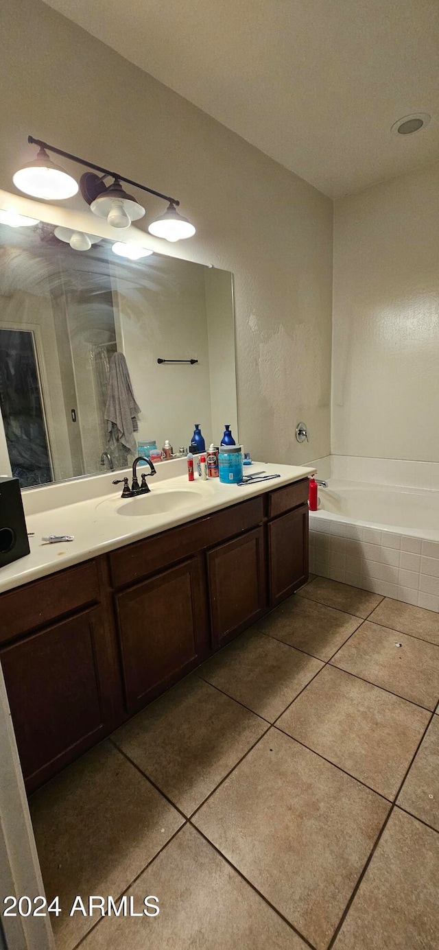 bathroom with vanity, a relaxing tiled tub, and tile patterned floors