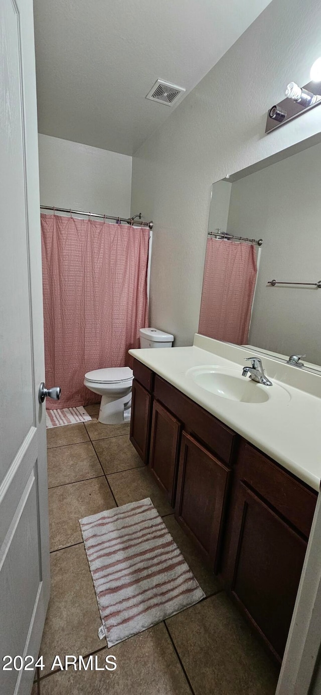 bathroom with toilet, vanity, and tile patterned floors