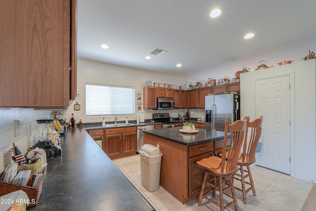 kitchen featuring appliances with stainless steel finishes, a breakfast bar, sink, a kitchen island, and light tile patterned flooring