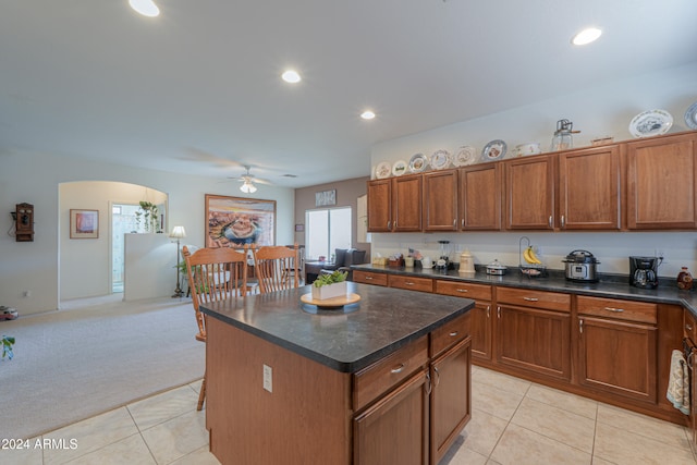 kitchen with ceiling fan, a center island, and light colored carpet