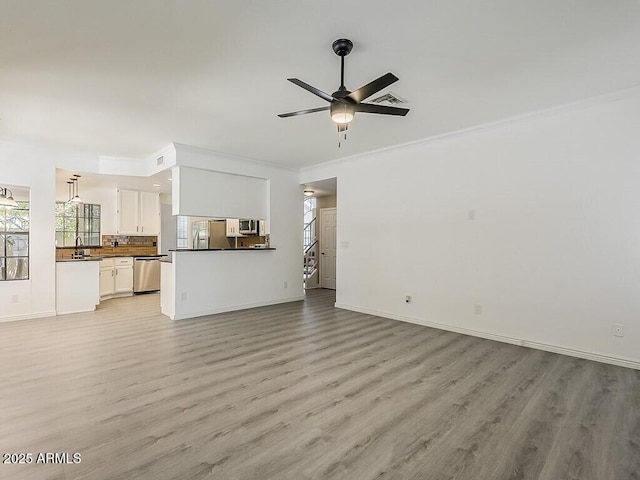 13064 N 100th Pl, Scottsdale, AZ 85260 - unfurnished living room featuring light wood-style floors, ornamental molding, a ceiling fan, baseboards, and a sink
