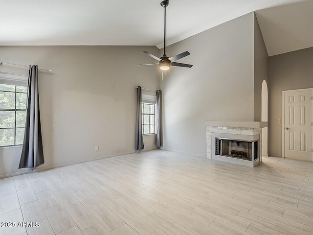 13064 N 100th Pl, Scottsdale, AZ 85260 - unfurnished living room featuring ceiling fan, healthy amount of natural light, arched walkways, light wood-style flooring, and high vaulted ceiling
