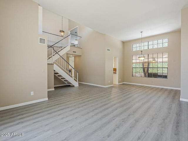 13064 N 100th Pl, Scottsdale, AZ 85260 - unfurnished living room featuring a high ceiling, wood finished floors, baseboards, and stairway