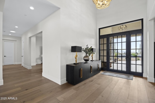 entryway with french doors, an inviting chandelier, and hardwood / wood-style flooring