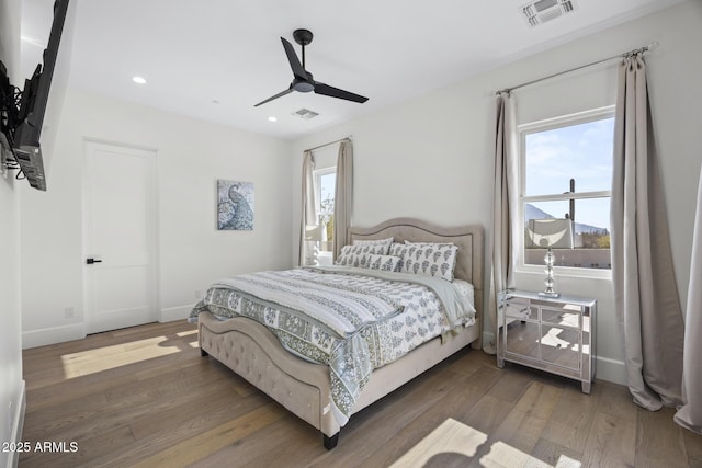 bedroom featuring ceiling fan, multiple windows, and dark hardwood / wood-style flooring