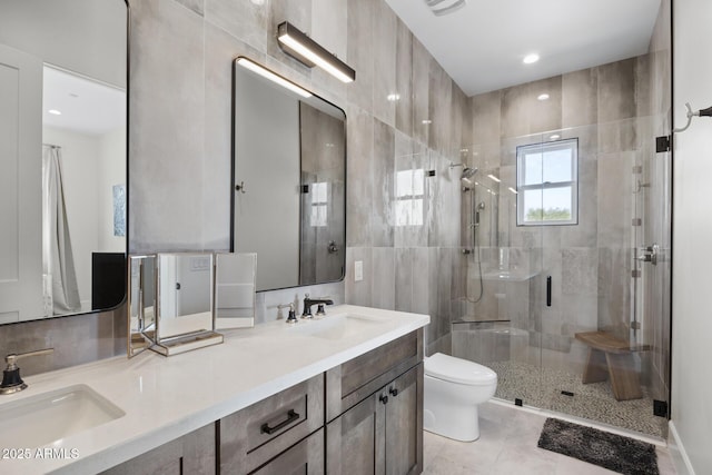 bathroom with toilet, vanity, tile walls, tile patterned flooring, and a shower with door