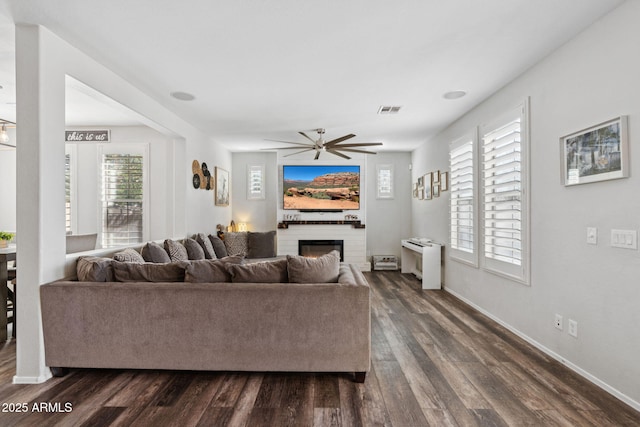 20518 W White Rock Rd, Buckeye, AZ 85396 - living room featuring dark wood finished floors, a glass covered fireplace, and ceiling fan