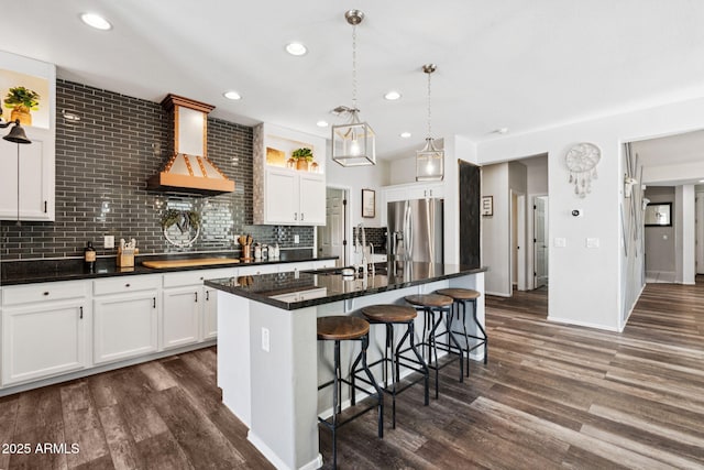 20518 W White Rock Rd, Buckeye, AZ 85396 - kitchen with stainless steel fridge, exhaust hood, dark wood finished floors, a kitchen breakfast bar, and white cabinets