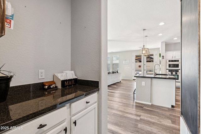 20518 W White Rock Rd, Buckeye, AZ 85396 - kitchen featuring white cabinetry, light wood-style flooring, recessed lighting, pendant lighting, and an island with sink