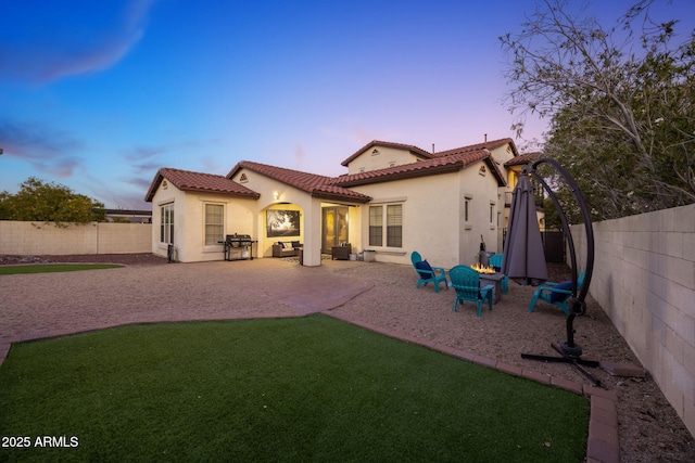 20518 W White Rock Rd, Buckeye, AZ 85396 - back of property at dusk featuring stucco siding, a fenced backyard, a patio area, and a tile roof