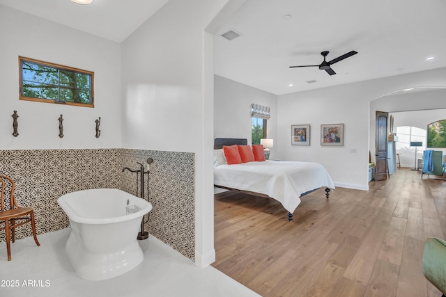 bedroom featuring billiards, ceiling fan, light hardwood / wood-style floors, and tile walls