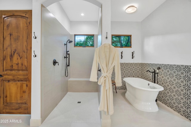 bathroom featuring shower with separate bathtub and tile walls