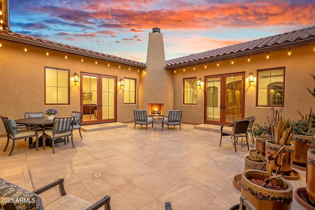 patio terrace at dusk with a fire pit and french doors