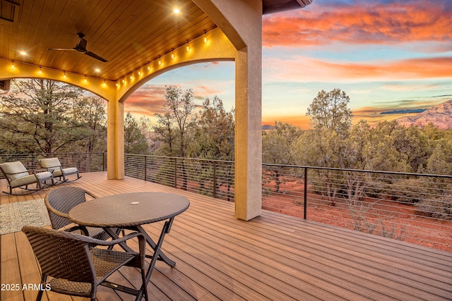 deck at dusk featuring ceiling fan