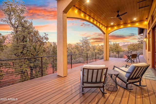 deck at dusk featuring ceiling fan