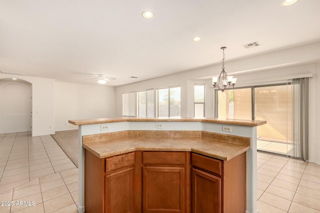 kitchen featuring pendant lighting, light tile patterned floors, ceiling fan with notable chandelier, and a kitchen island