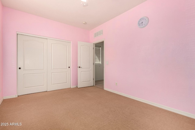 unfurnished bedroom with light carpet and a closet